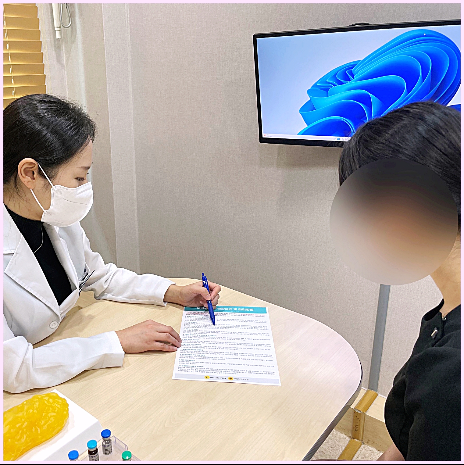 춘천검버섯제거 전문 후한의원 춘천점 원장이 환자에게 안내문을 설명하는 장면