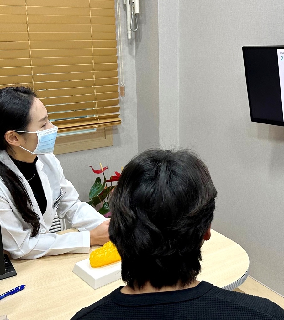 원장이 환자와 함께 모니터 자료를 보며 치료 내용을 설명하는 진료실 상담 장면